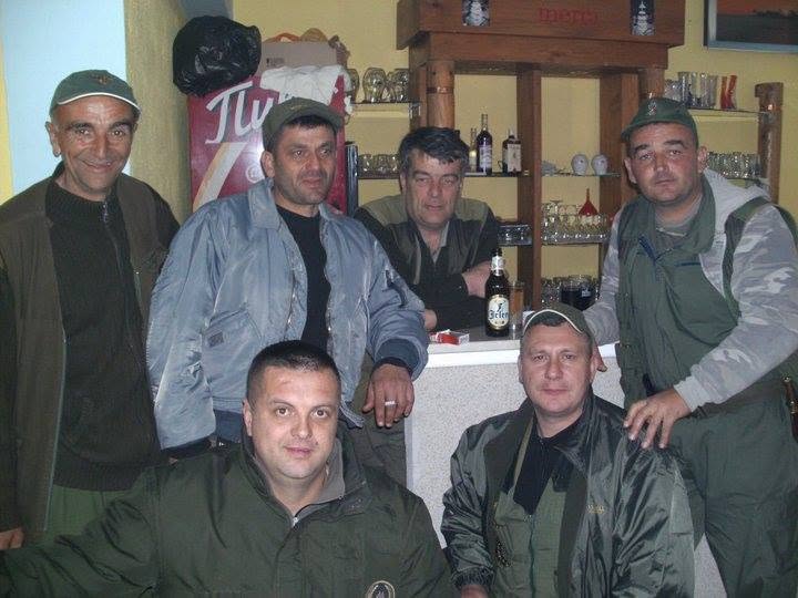 Članovi u lovačkim jaknama na zajedničkom druženju u zatvorenom prostoru